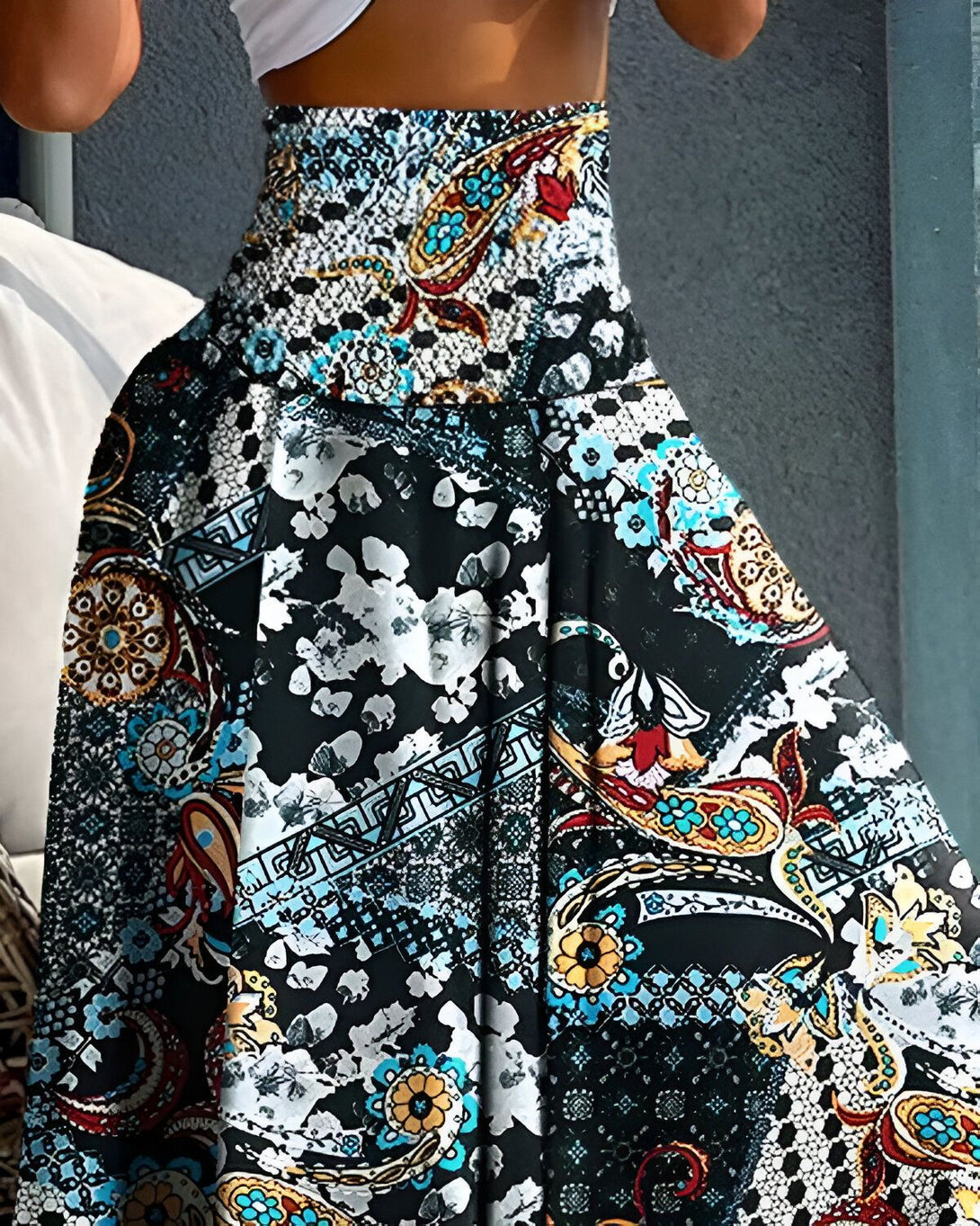 Une femme porte une jupe longue et ample à taille haute. La jupe est noire avec des motifs colorés.