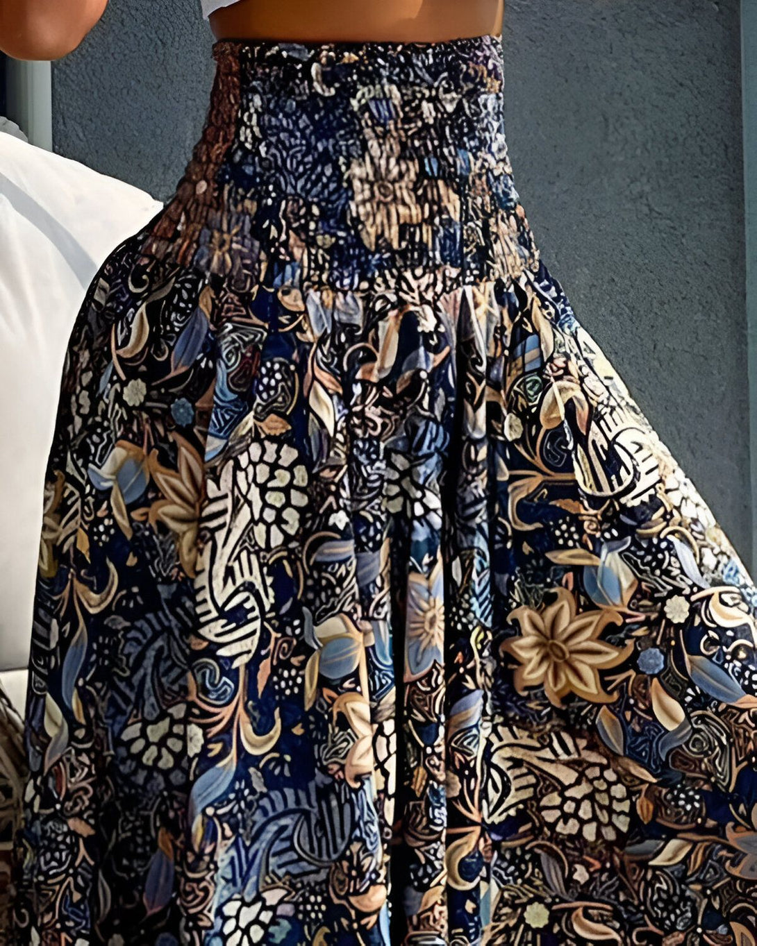 Une femme porte une jupe longue et ample à taille haute. La jupe est bleu marine et marron, et présente un motif floral.