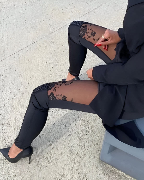 Une femme porte un legging noir avec des empiècements en dentelle. Elle porte également des escarpins noirs et un blazer noir.