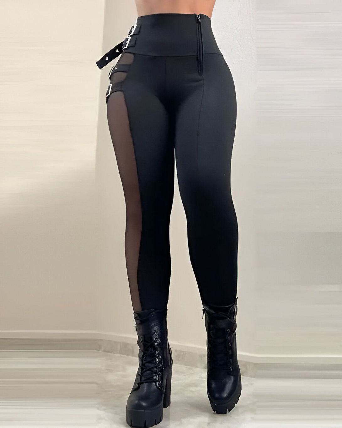 Une femme porte un legging noir avec des empiècements en résille sur les côtés. Elle porte également des bottes noires à lacets.