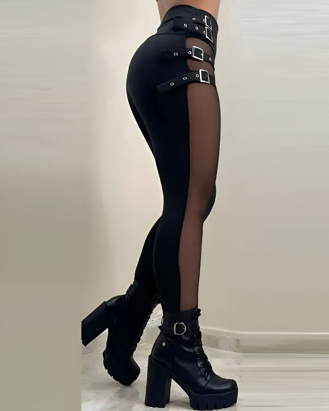 Une femme porte un legging noir avec des empiècements en résille sur les côtés. Elle porte également des bottes noires à talons hauts.