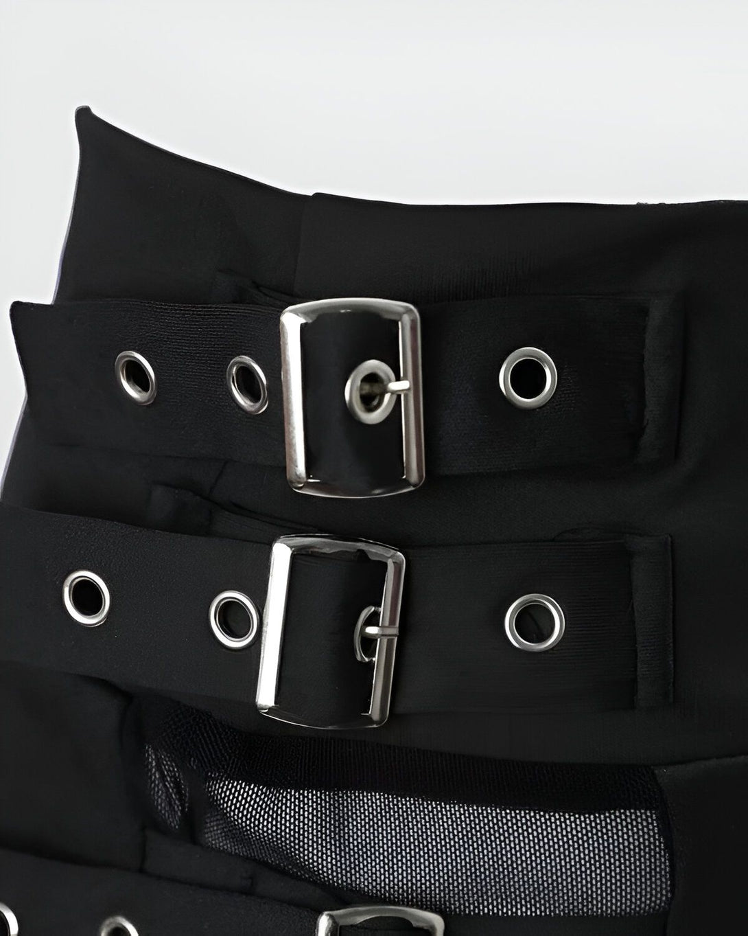 Une image d'une jupe noire avec des boucles de ceinture en métal. La jupe est faite d'un tissu en maille transparent.