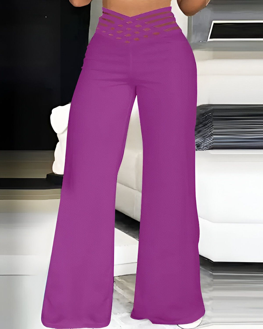 Une femme porte un pantalon taille haute évasé violet. Le pantalon est en stretch et possède une ceinture croisée sur le devant.