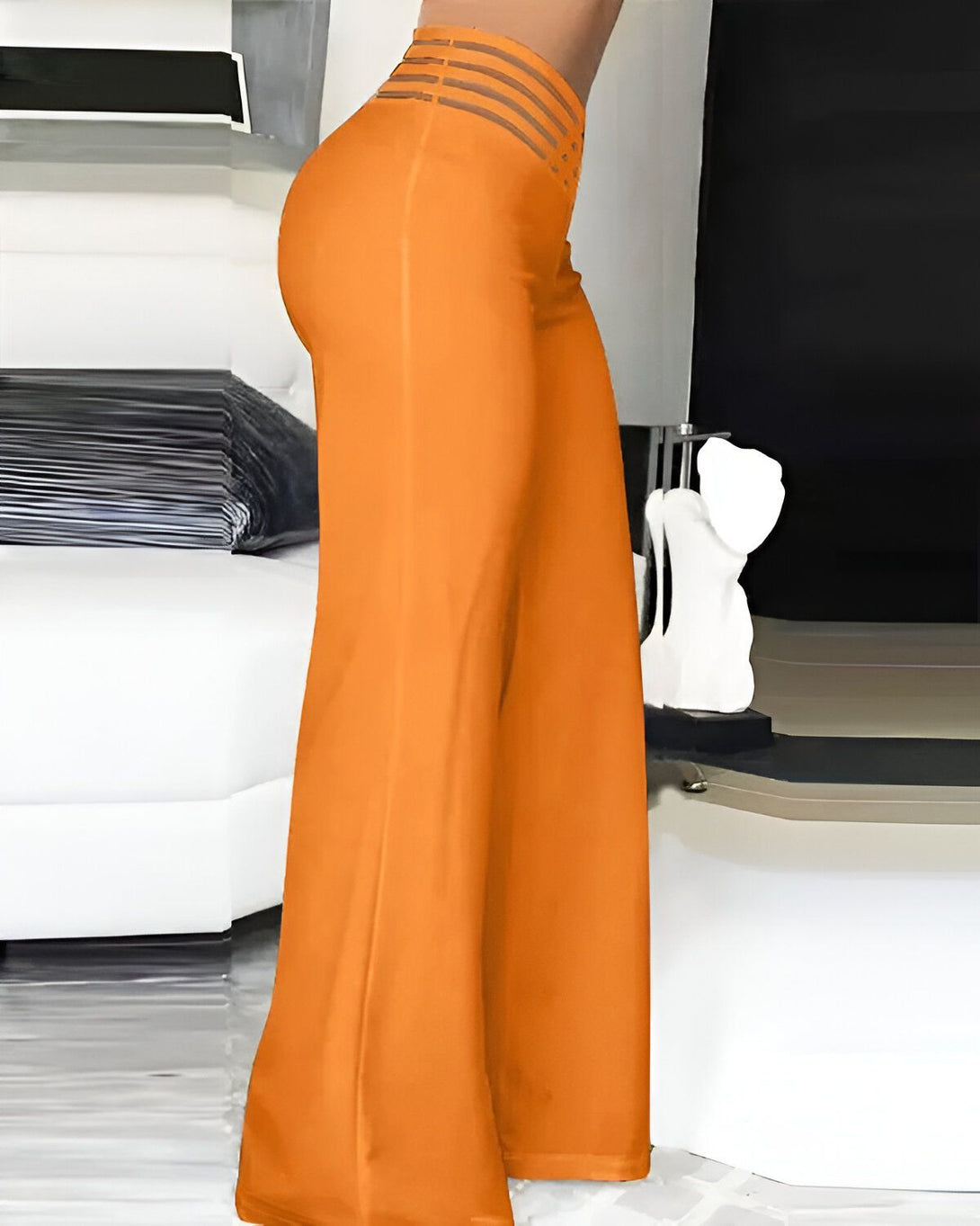 Une femme porte un pantalon orange taille haute évasé.