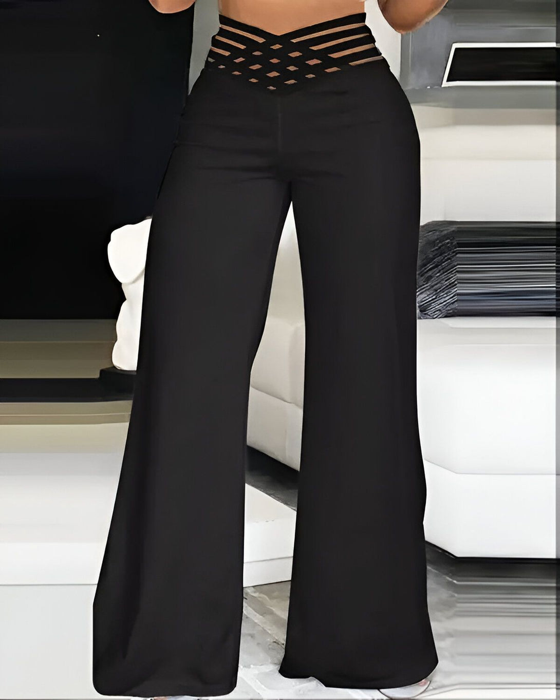 Une femme porte un pantalon large noir taille haute avec un haut court noir.