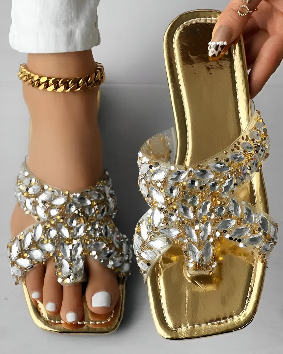 Une paire de sandales dorées à talons hauts avec des brides transparentes et des strass.