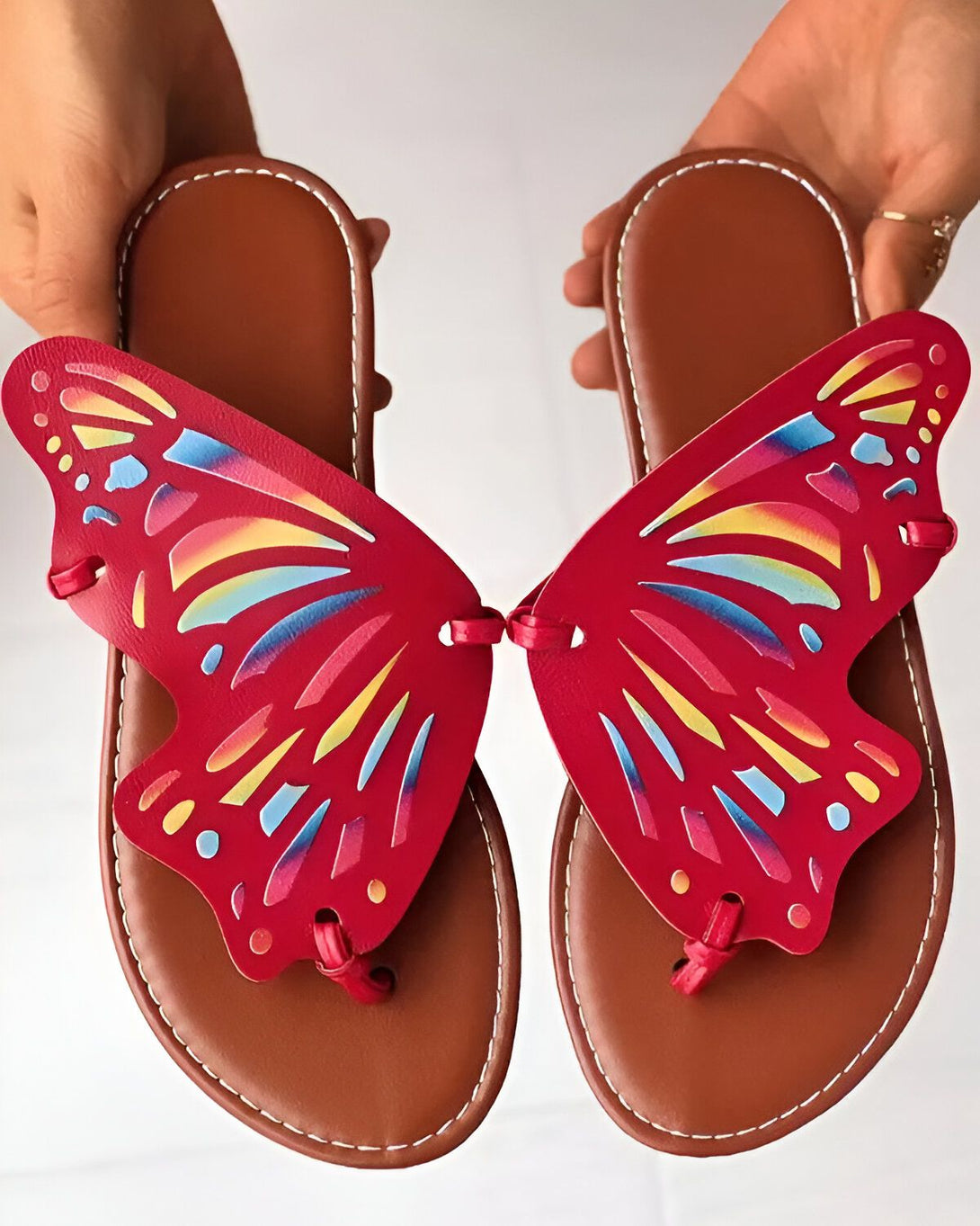 Une paire de tongs rouges en forme de papillon avec des ailes colorées.