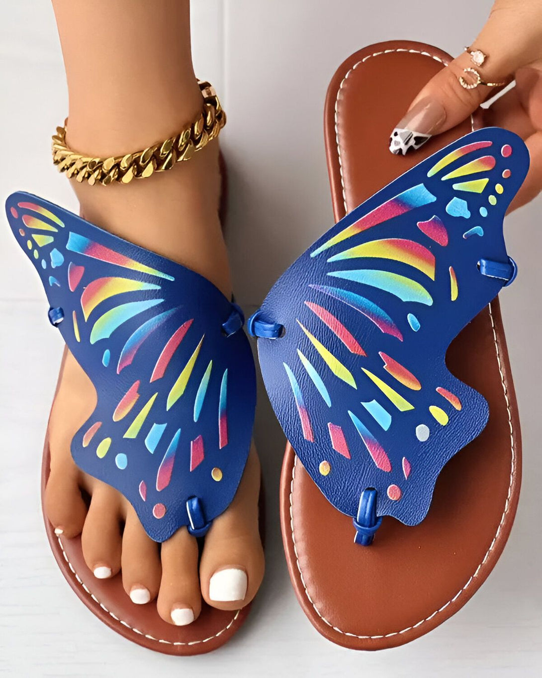 Une paire de sandales plates bleues en forme de papillon avec des ailes colorées.