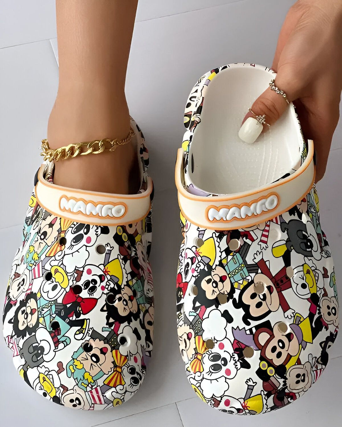 Une paire de sabots blancs avec des motifs de dessins animés. Les sabots sont de la marque Mamo.