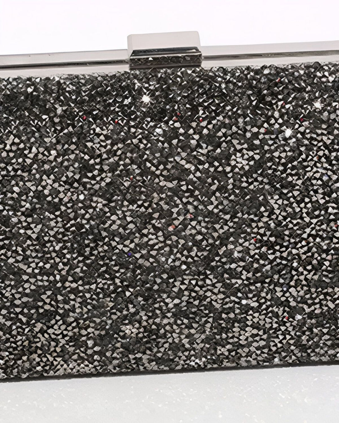 Une image d'une minaudière argentée avec des paillettes noires et une anse argentée. La minaudière est ouverte et on peut voir l'intérieur en satin noir.