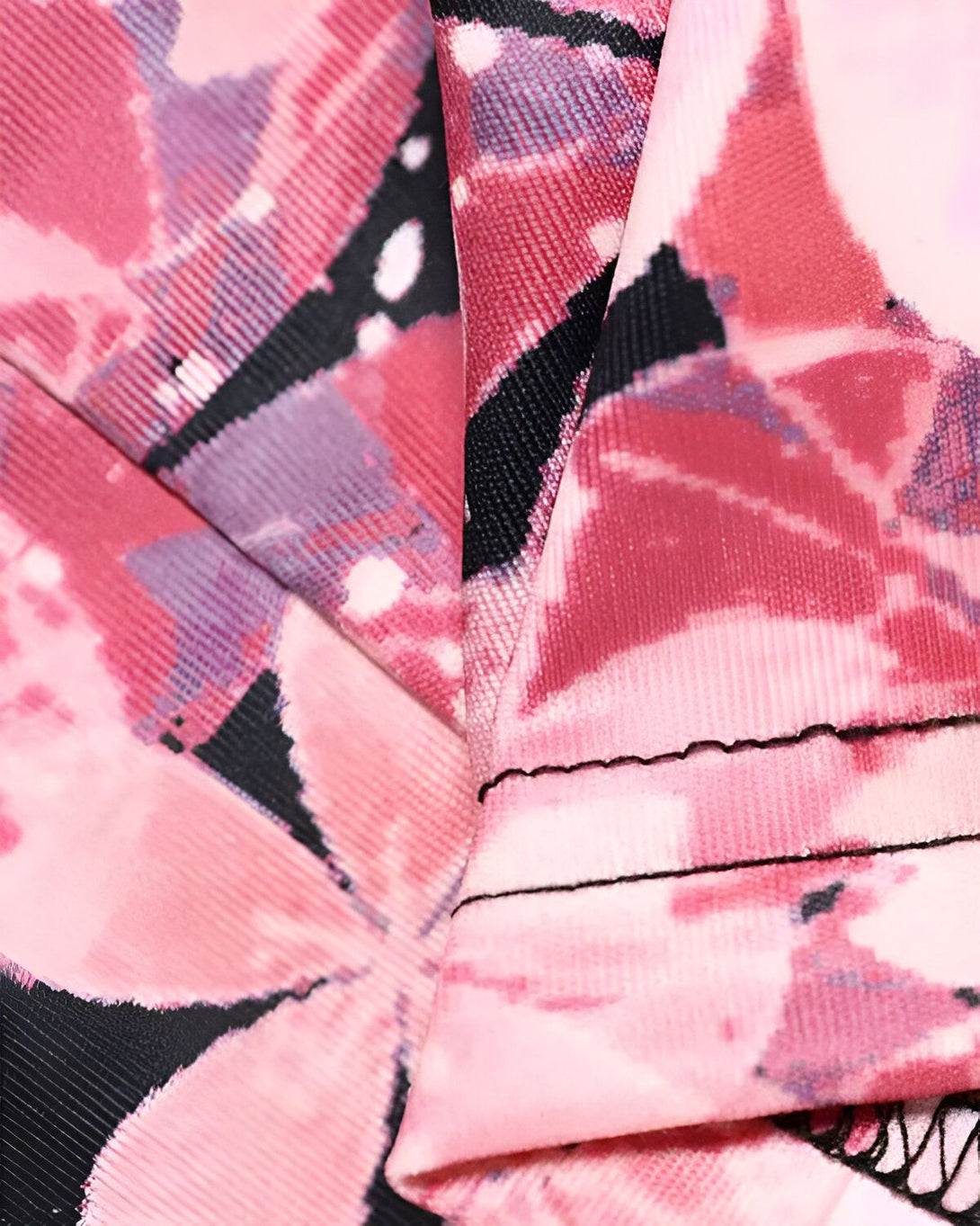 Une image de tissu rose avec des motifs floraux noirs et mauves.