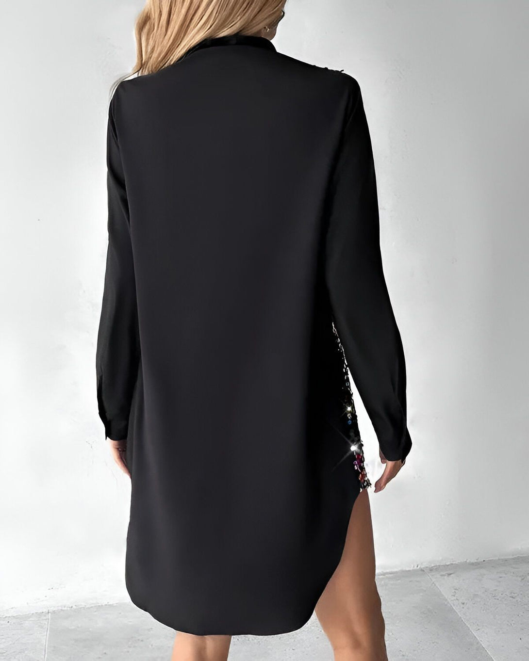 Une femme porte une chemise noire à manches longues ouverte dans le dos avec des sequins multicolores sur le bas.