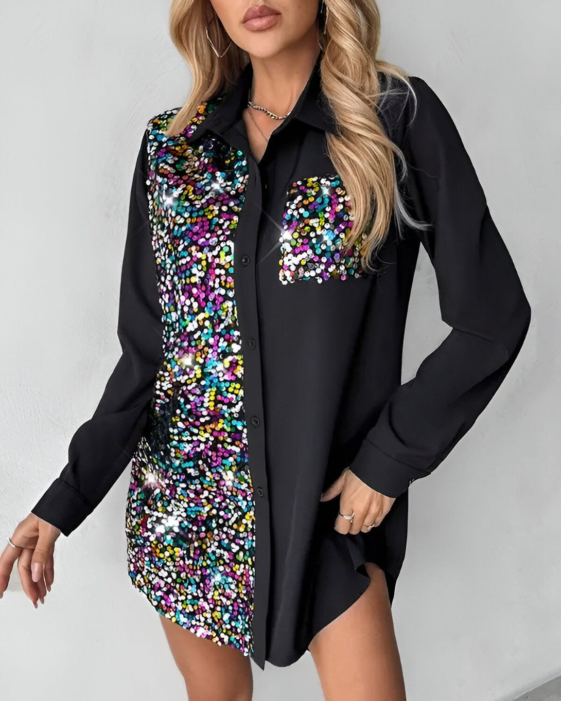 Une jeune femme porte une chemise noire à manches longues. La moitié de la chemise est recouverte de paillettes multicolores.