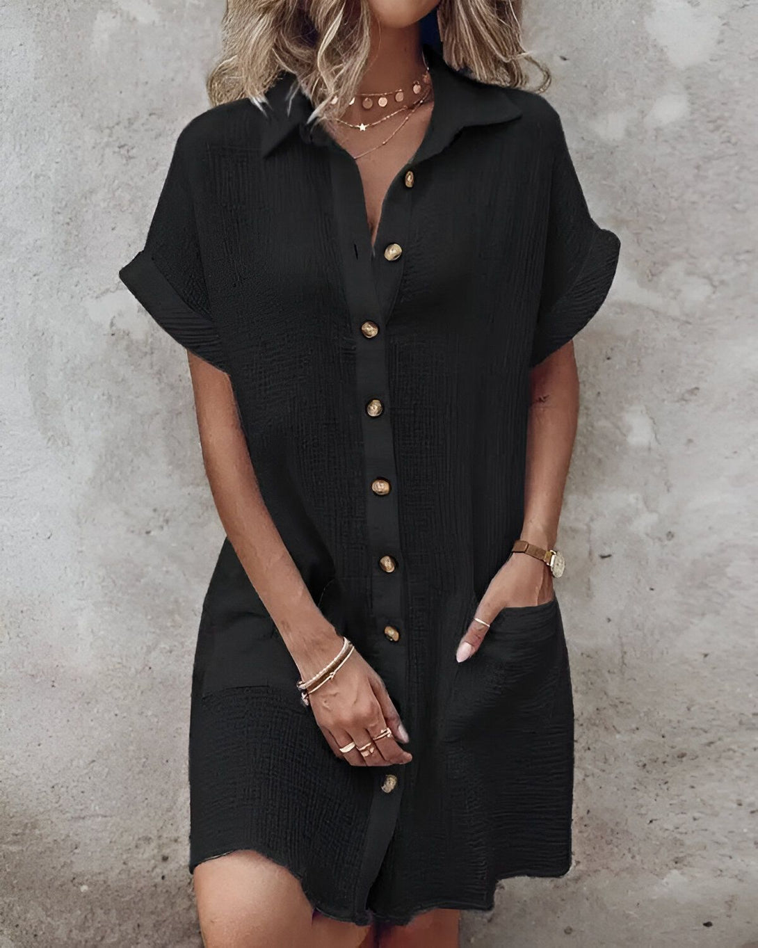 Une femme porte une chemise noire oversize avec des boutons et des poches.