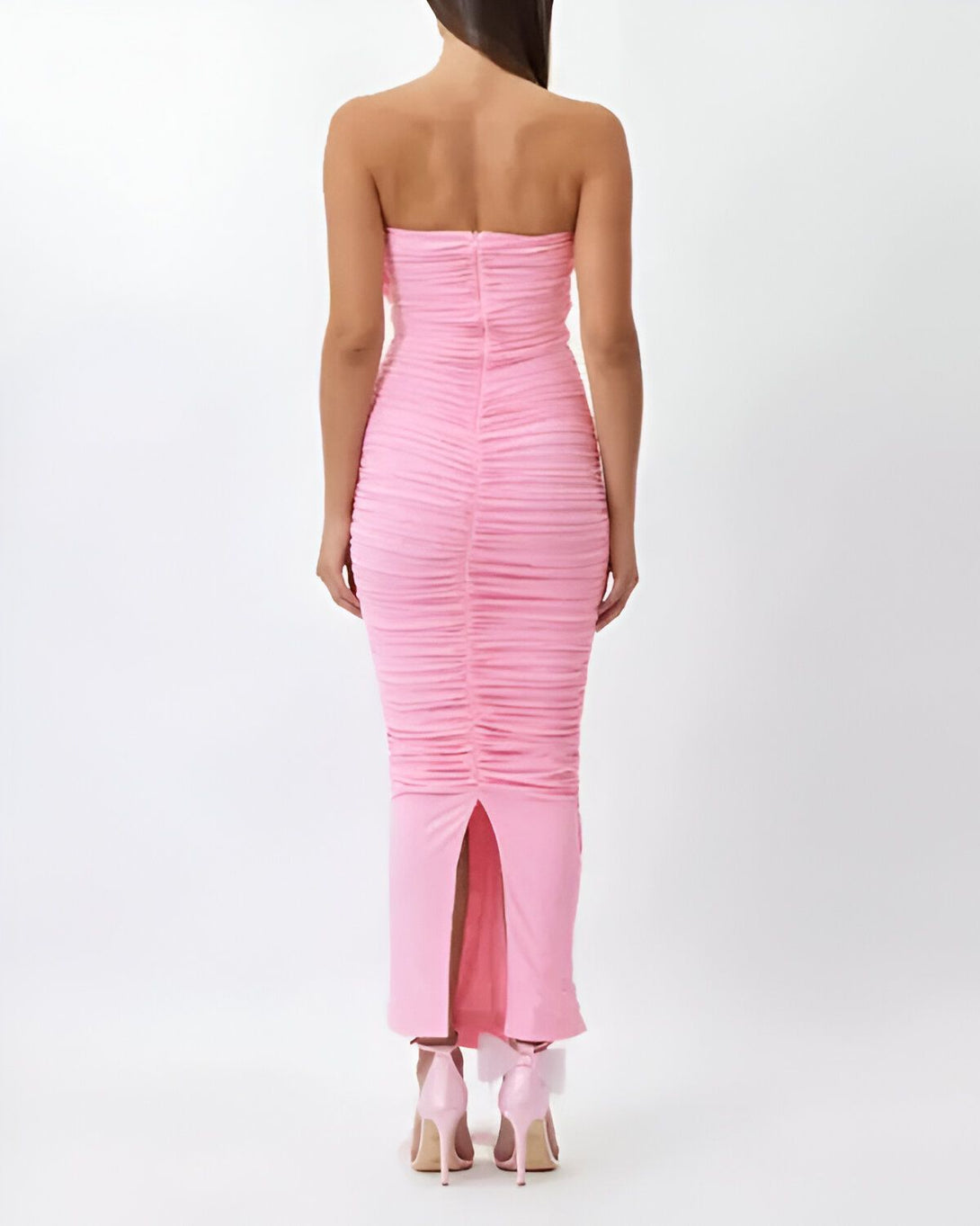 Une femme portant une robe rose dos nu avec une fente au niveau de la jambe.