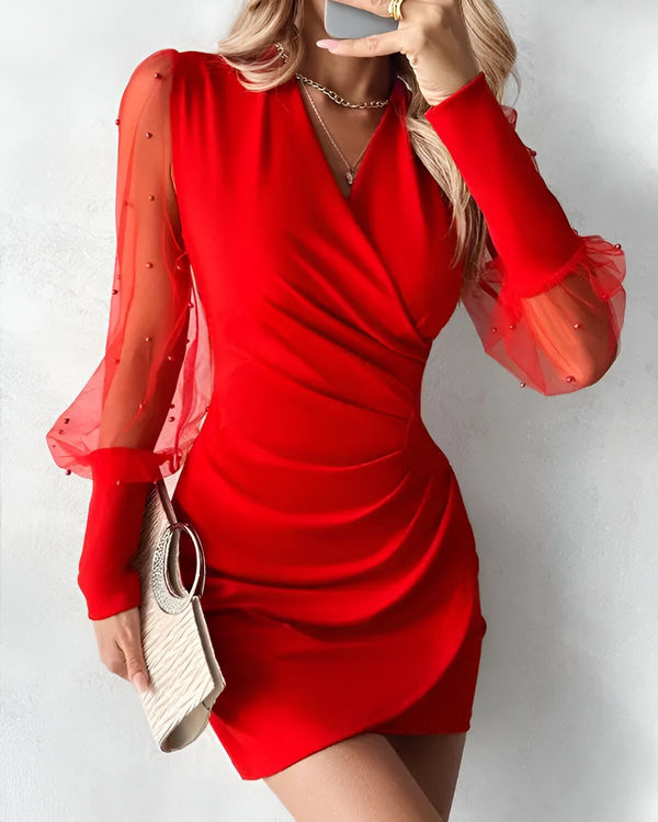 Une femme porte une robe rouge moulante avec des manches bouffantes en tulle perlé.
