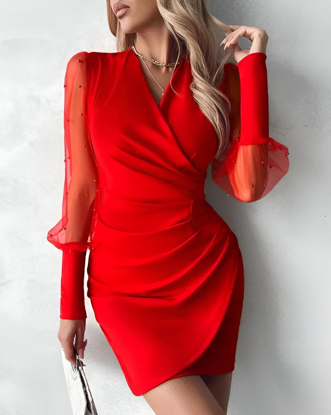 Une femme porte une robe rouge moulante avec des manches bouffantes en tulle perlé.