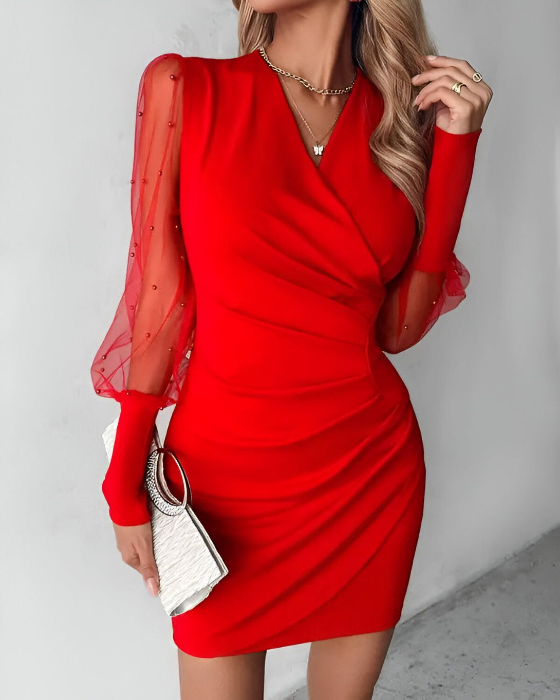 Une femme porte une robe rouge moulante avec des manches bouffantes en tulle perlé.