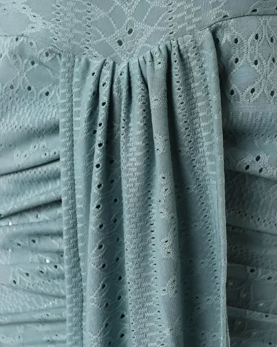 Une image d'un tissu vert pâle avec des motifs floraux et des trous.