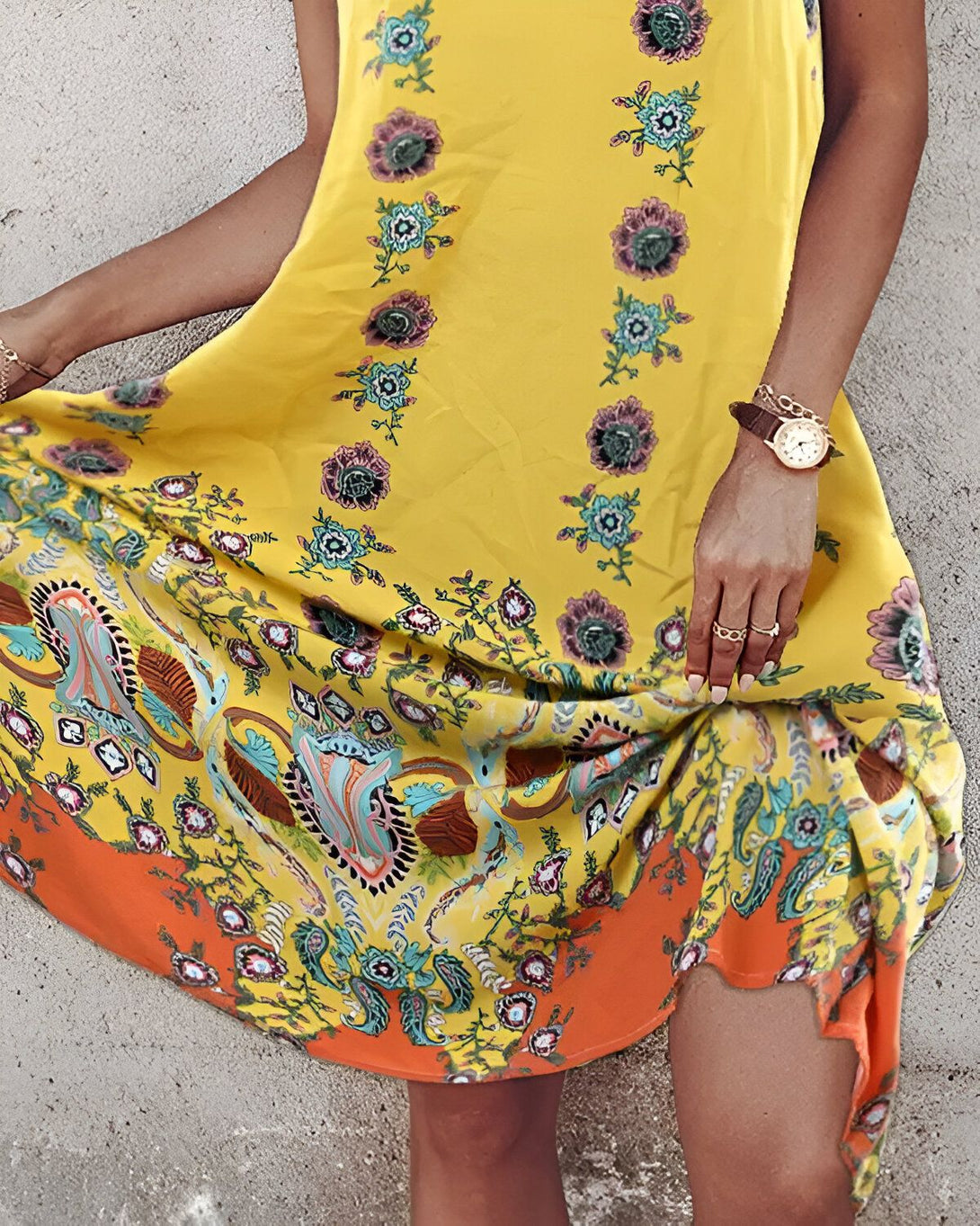 Une femme porte une robe jaune à motifs floraux et un bracelet de montre marron.
