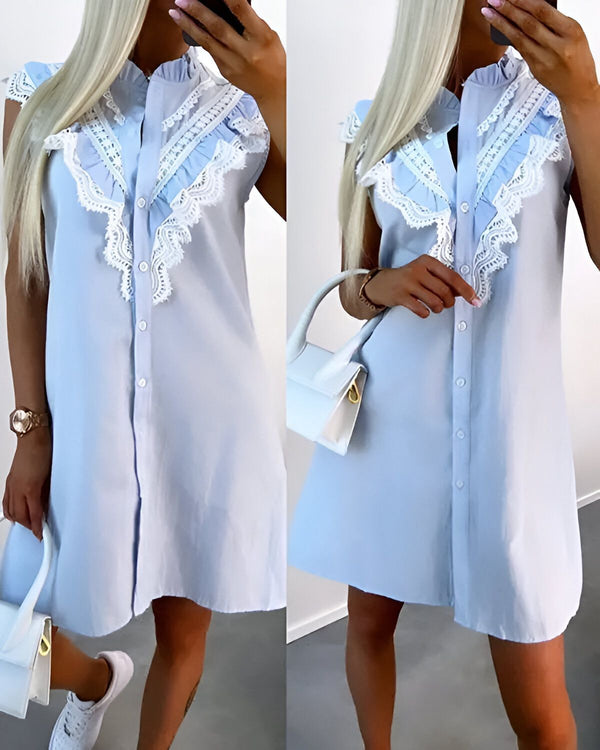 Une jeune femme porte une robe chemise bleu clair. La robe est sans manches et possède un col montant. Elle est ouverte sur le devant et possède des boutons. La femme porte également un sac à main blanc et des baskets blanches.