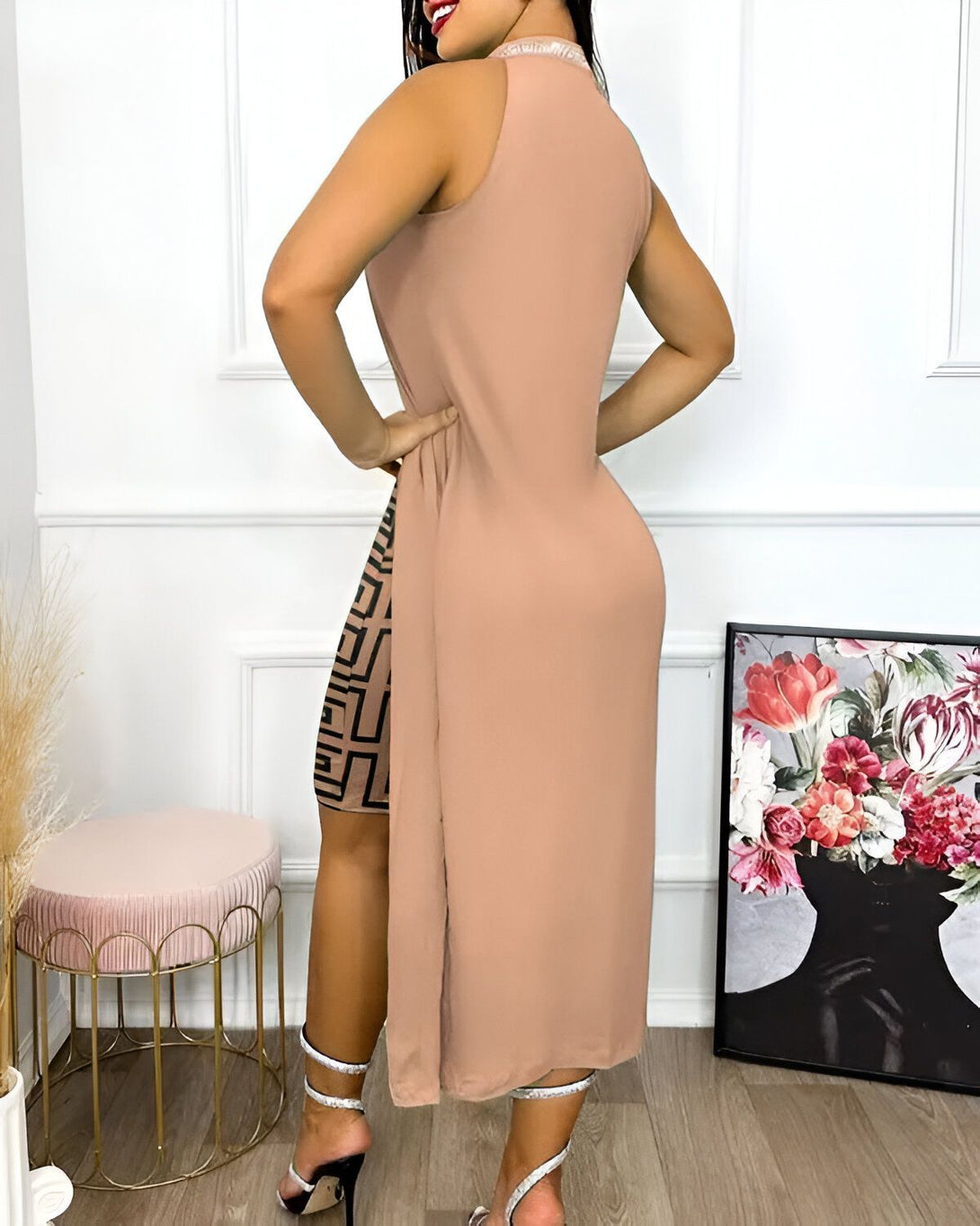 Une femme porte une robe longue beige avec un imprimé graphique marron et noir. La robe est fendue sur le côté et elle porte des sandales à talons marron.