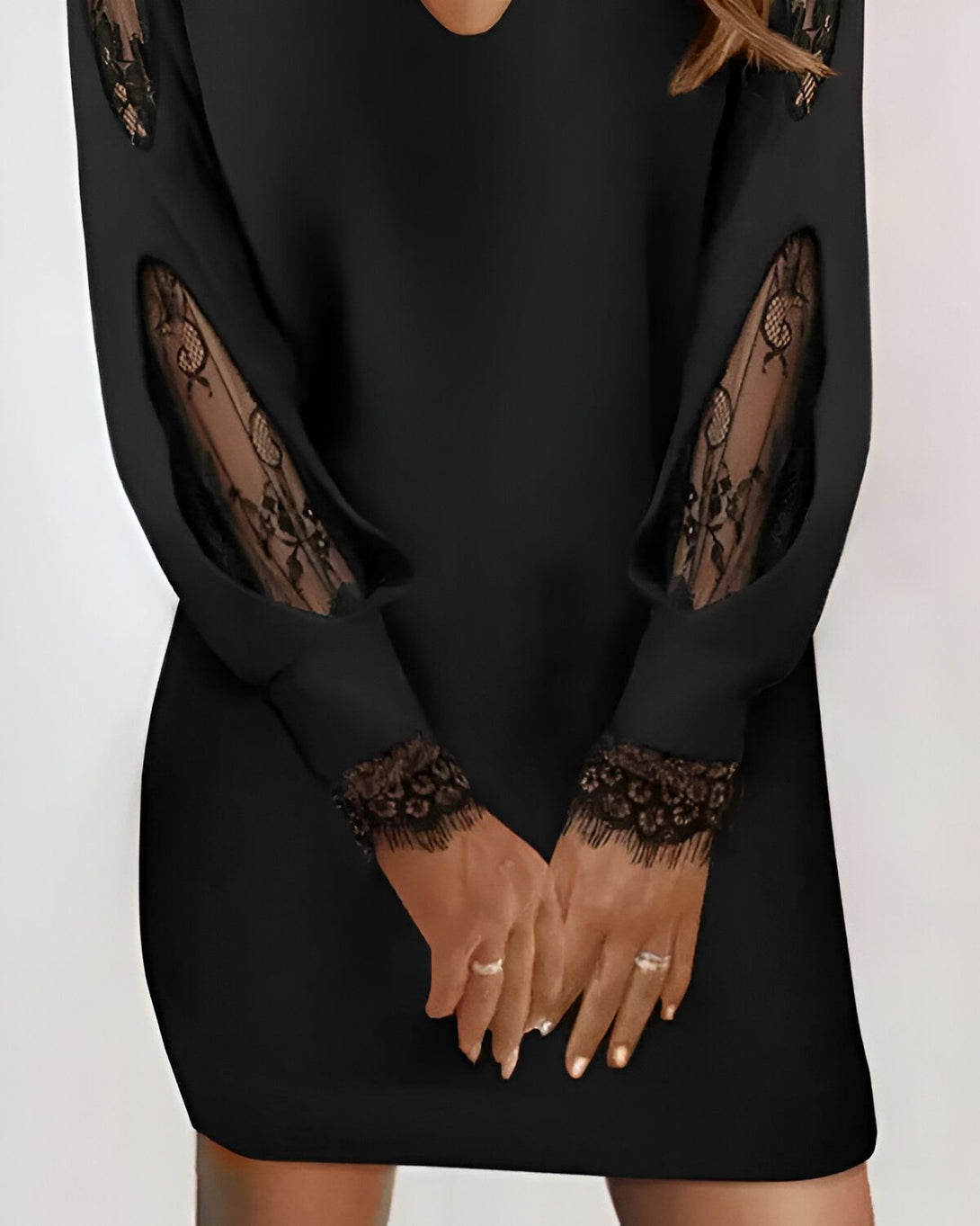 Une femme porte une robe noire moulante avec des manches en dentelle.