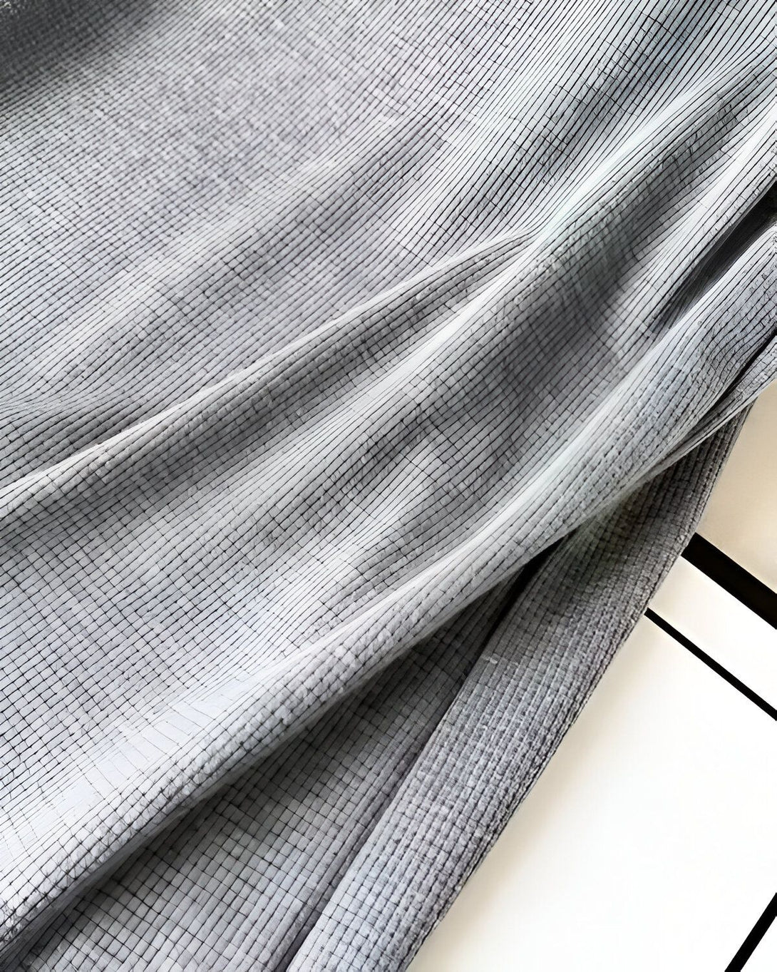 Une image d'un tissu gris texturé avec des reflets de lumière.