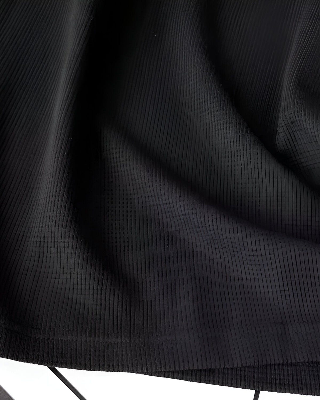 Une image en gros plan d'un tissu noir texturé. Le tissu est plissé et on peut voir les détails de la texture.