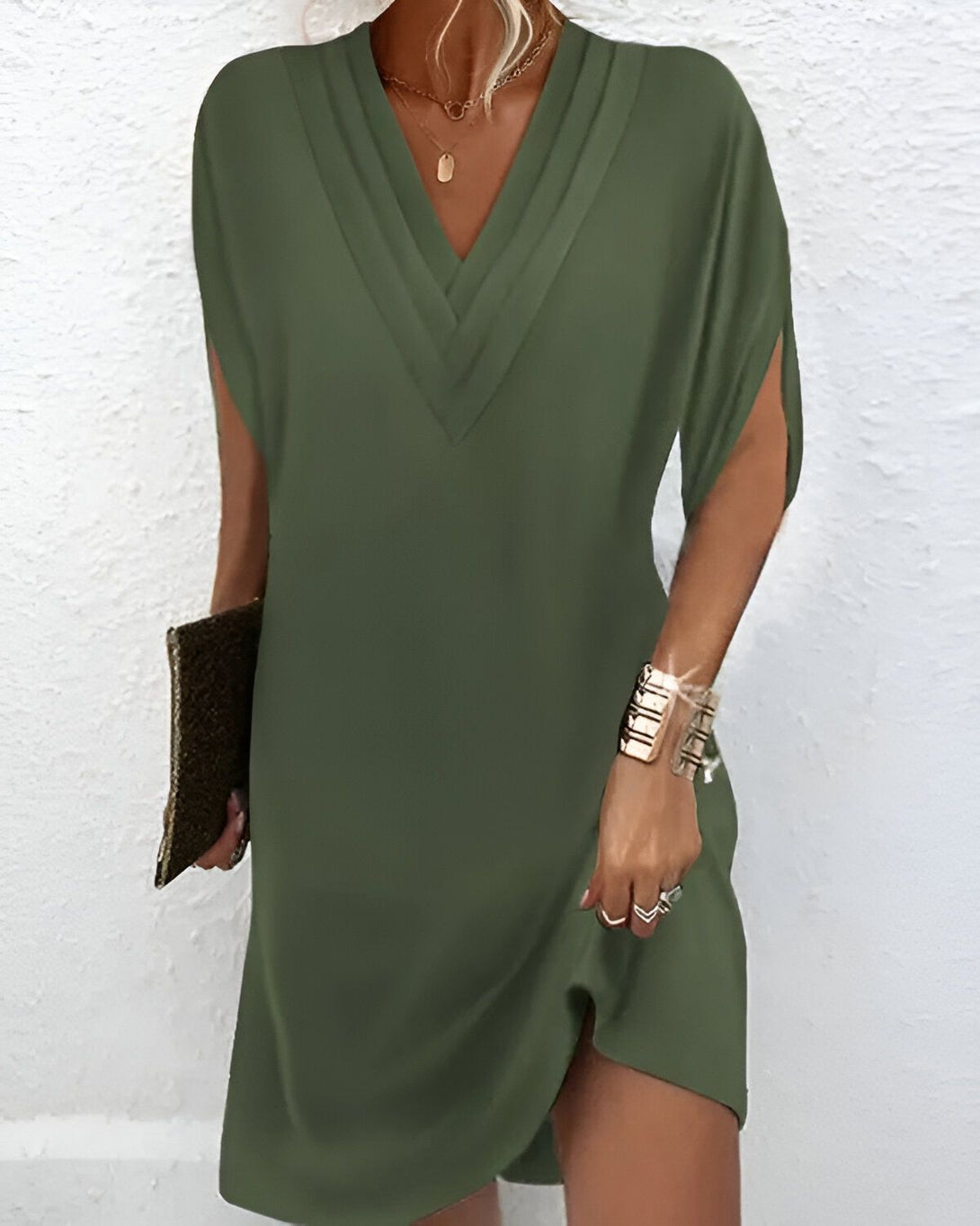 Une femme porte une robe verte courte à manches courtes avec un décolleté en V.