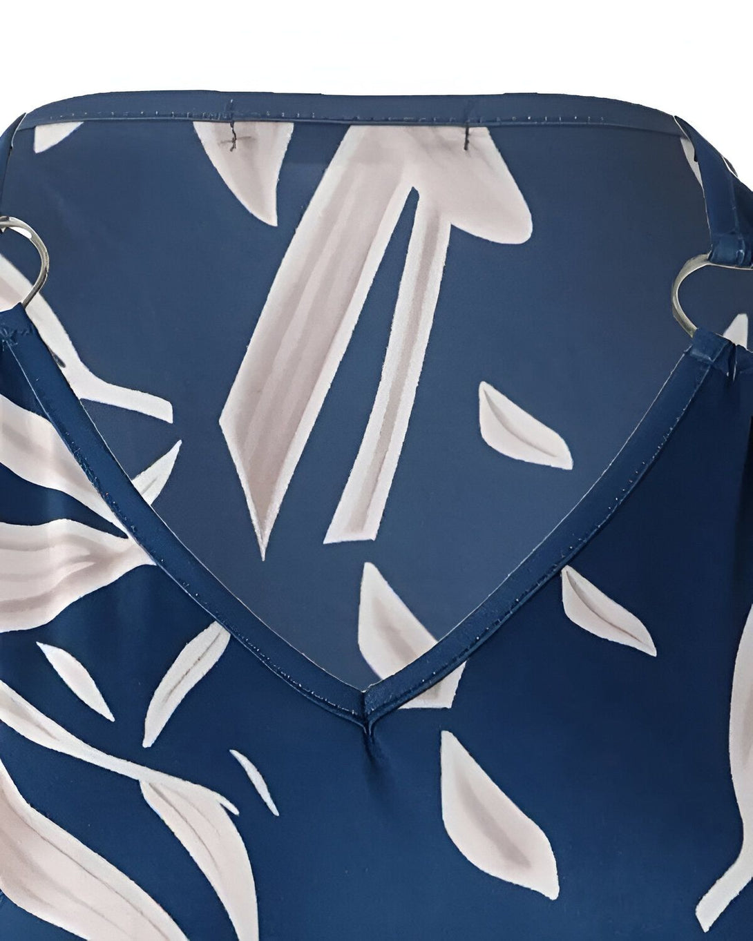 Une image d'une robe de soirée bleu marine à motifs de feuilles blanches. Le dos de la robe est en V et l'encolure est bordée d'anneaux métalliques.