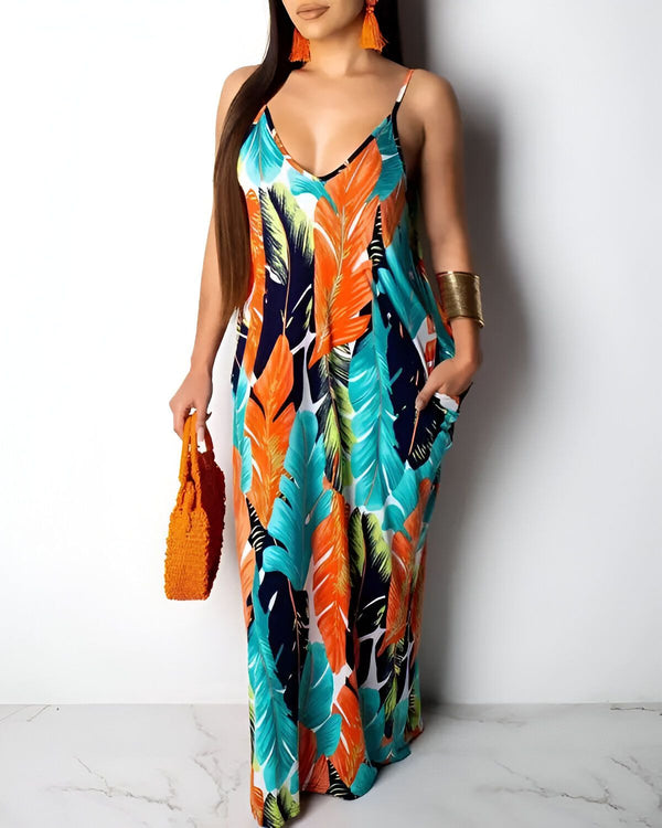 Une femme porte une longue robe d'été à fines bretelles. La robe est orange, verte et bleue et a un motif de feuilles tropicales. La femme porte également un sac à main orange et des boucles d'oreilles.
