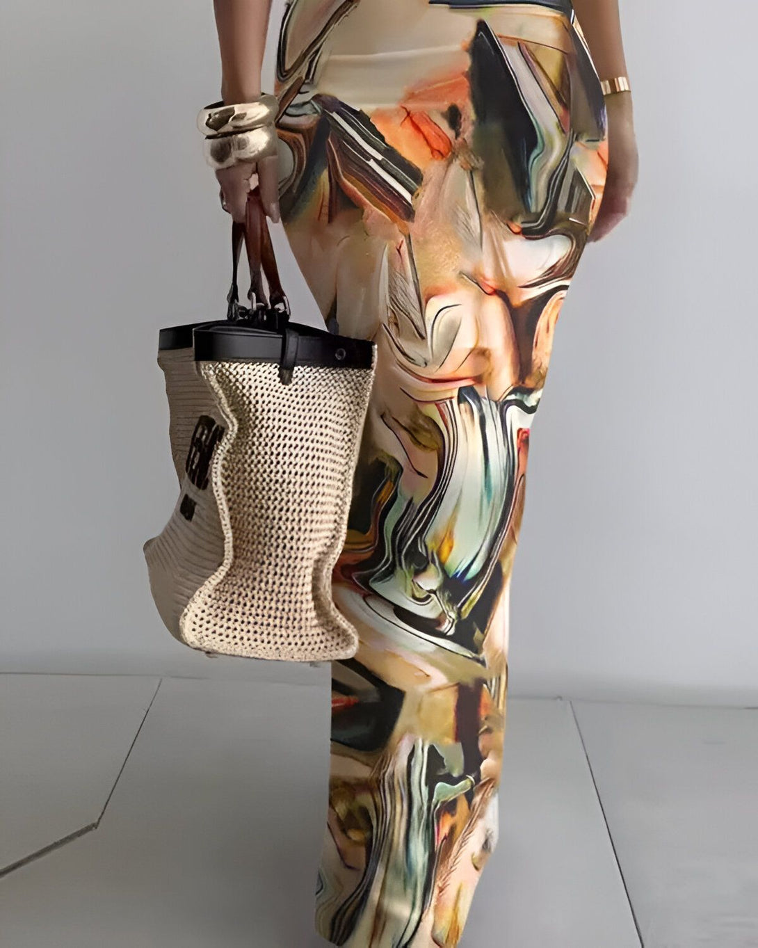 Une femme porte une longue robe colorée et un sac à main beige et marron.