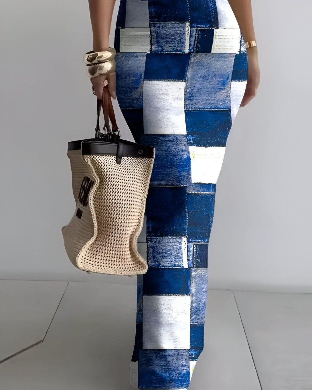 Une femme porte un pantalon long et moulant à motifs de carrés bleus et blancs. Elle porte également un sac à main beige et des talons hauts.