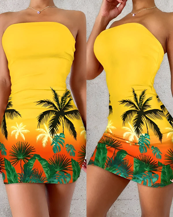 Une jeune femme porte une robe tube jaune sans bretelles. La robe est imprimée de palmiers et de feuilles tropicales.