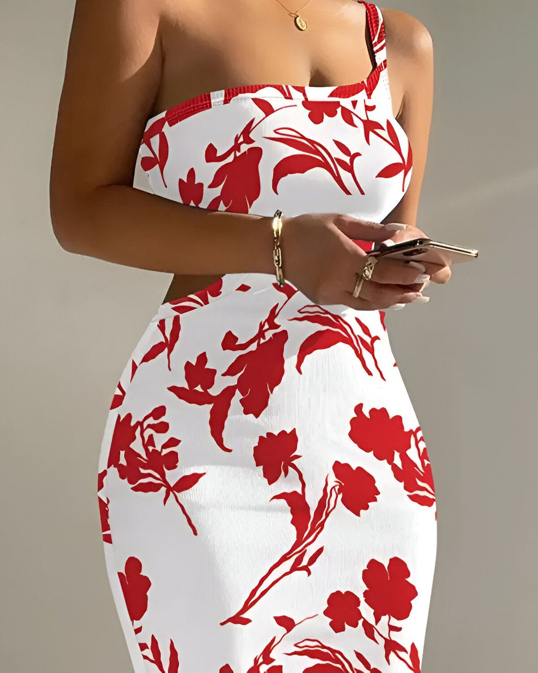 Une femme porte une robe blanche et rouge à motifs floraux. Elle tient un téléphone portable dans sa main droite.