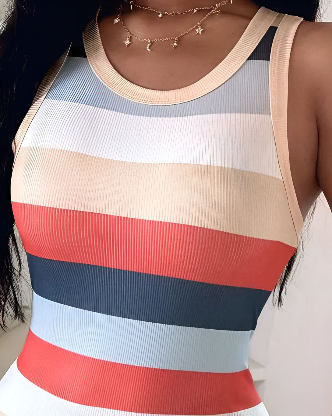 Une femme porte un débardeur côtelé à fines rayures horizontales multicolores.