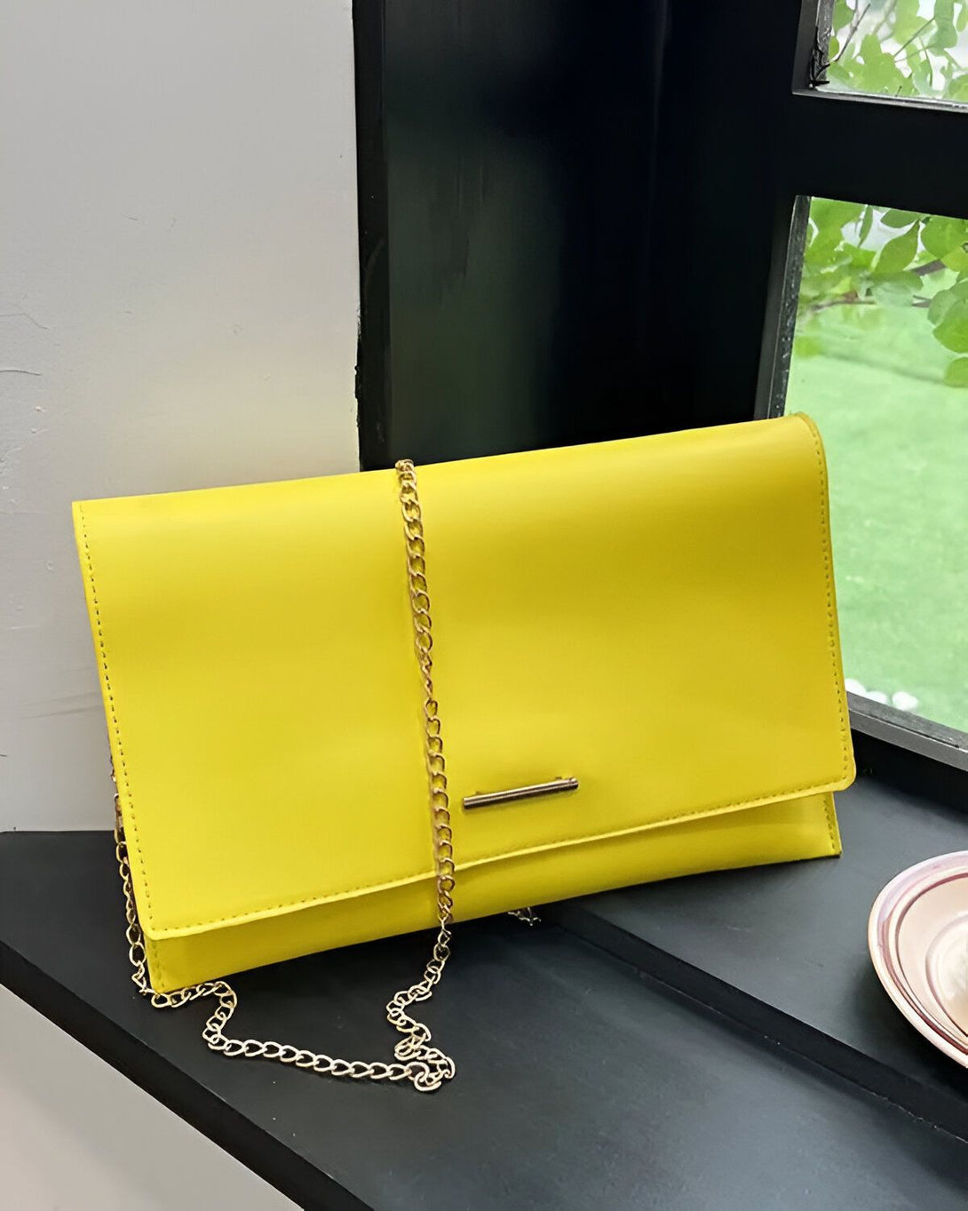 Une image d'une pochette jaune vif avec une chaîne dorée. La pochette est posée sur une surface noire.