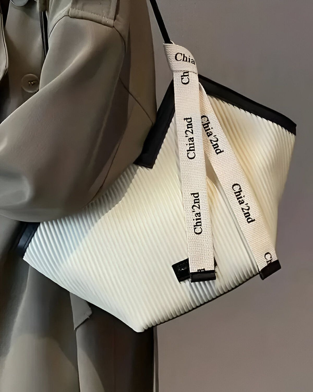 Une femme porte un cabas blanc à anse noire et blanche. Le cabas est de la marque Chia 2nd.