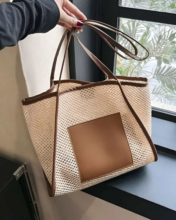 Une femme tient un sac à main beige et marron. Le sac est en filet et possède une grande anse. Il est porté à l'épaule.