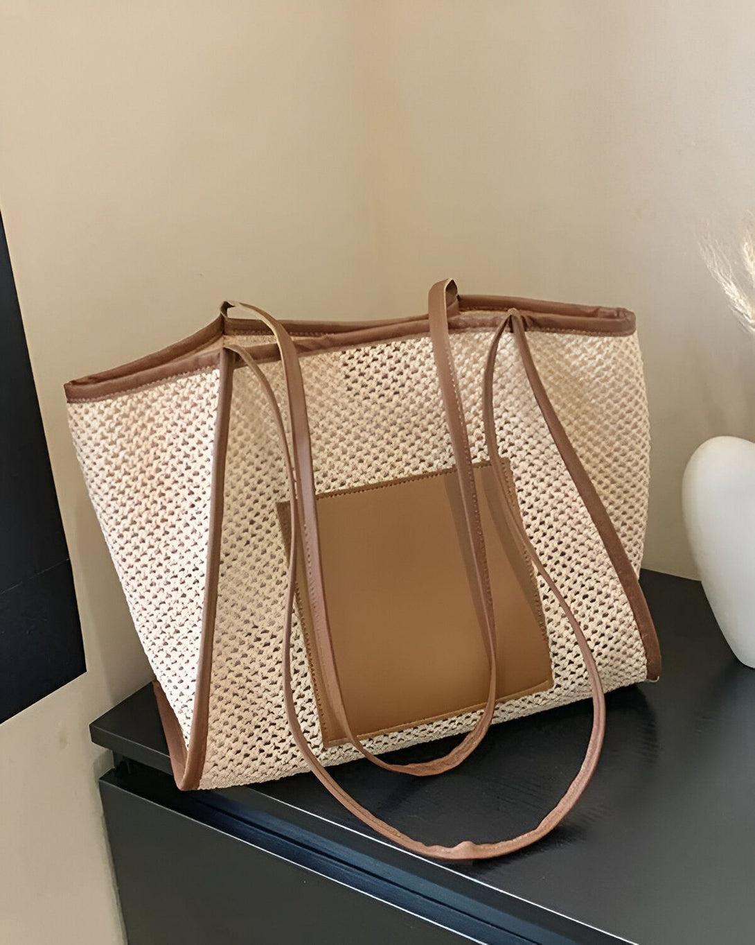 Un sac fourre-tout beige et marron avec une poche avant et de longues anses.