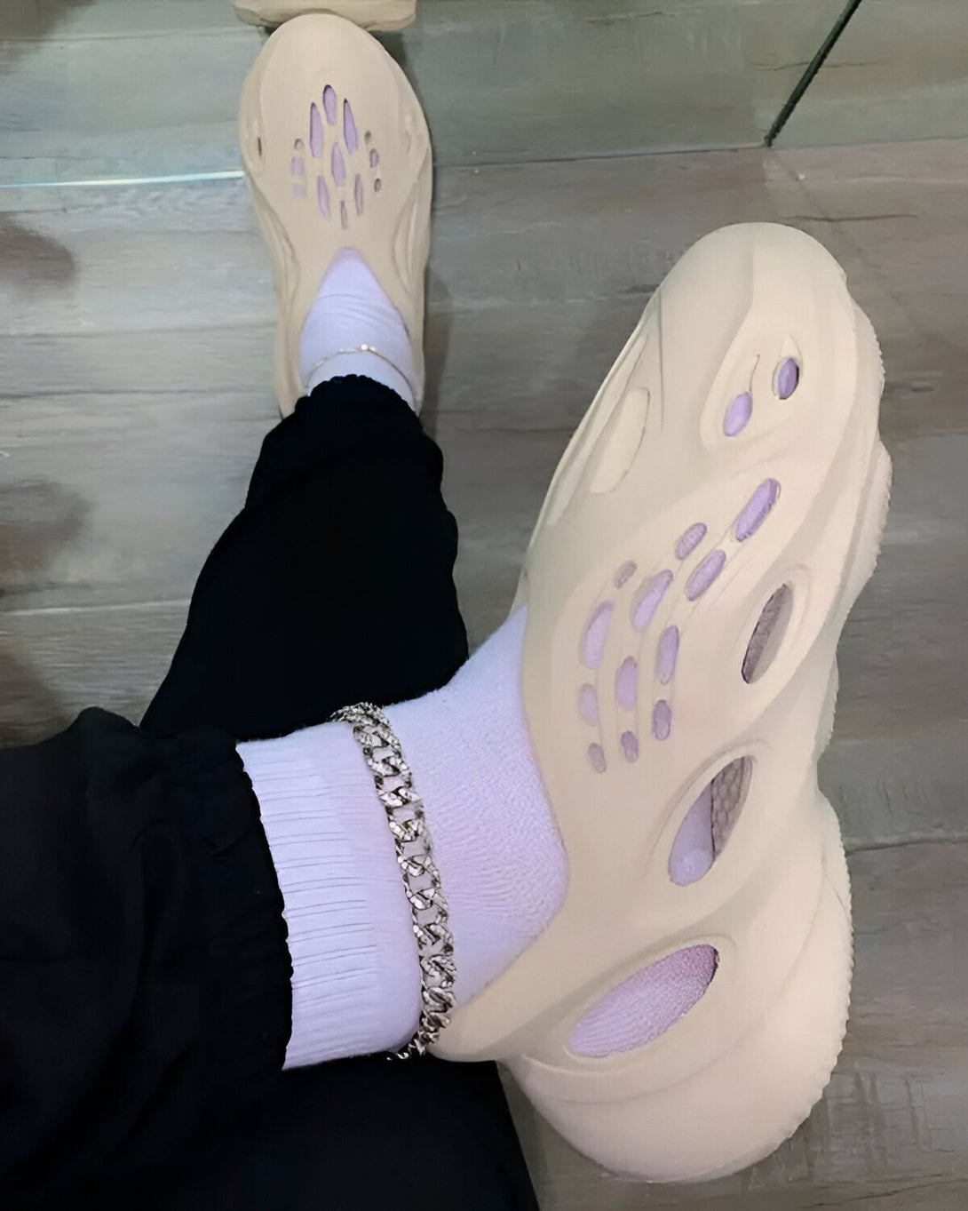 Une personne porte des chaussettes blanches et des sandales beige trouées.