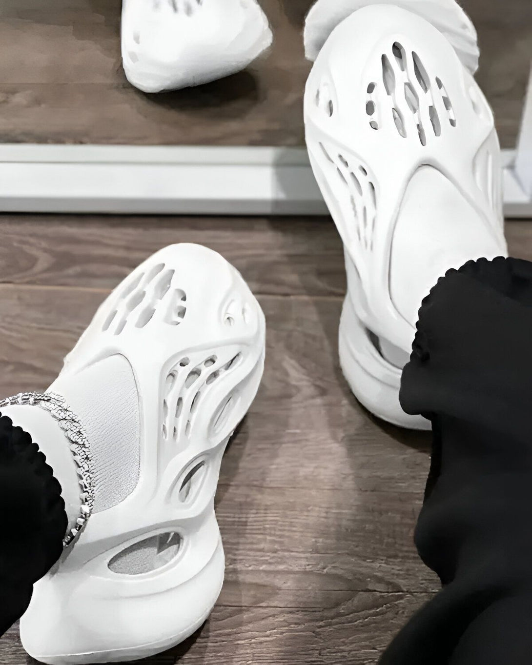 Une paire de chaussures Yeezy Foam Runner blanche est posée sur le sol.