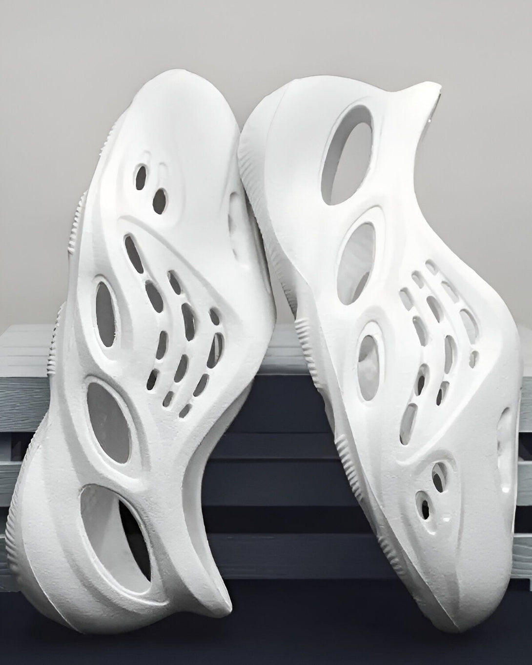 Une paire de chaussures Yeezy Foam Runner blanches. Les chaussures sont en mousse et ont un design unique avec des trous sur toute la surface.