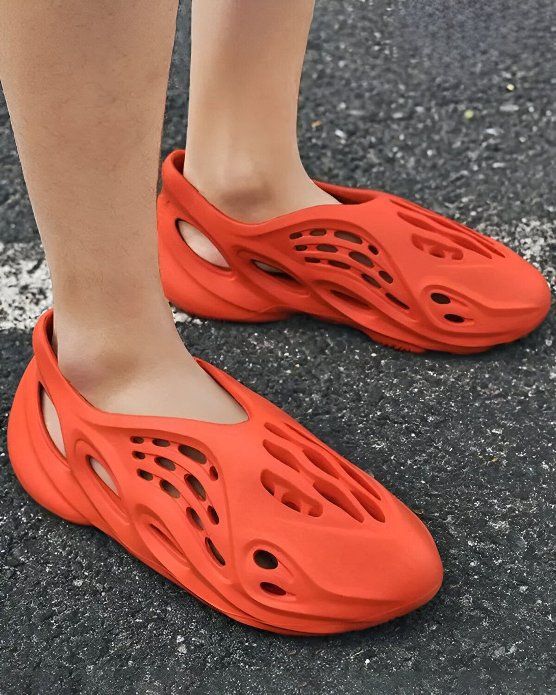 Une personne porte des sandales orange trouées.