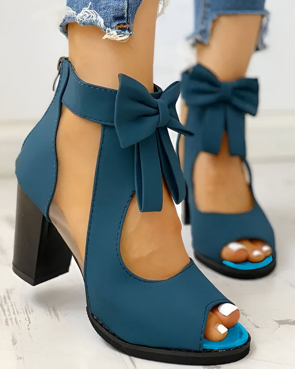 Une image de chaussures à talons hauts bleues avec un nœud sur le devant. Les chaussures sont portées par une femme qui porte un jean bleu.