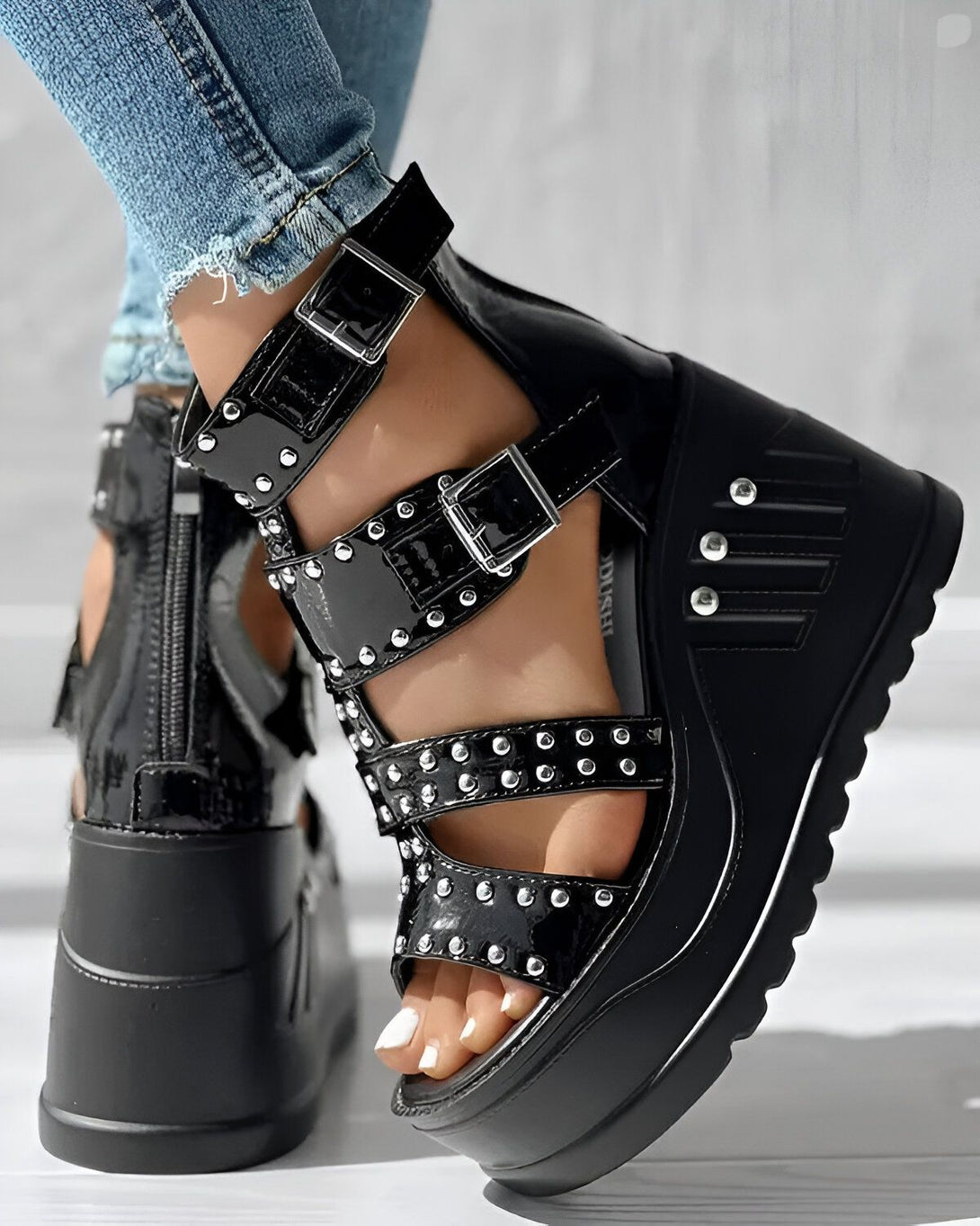 Une image d'une paire de sandales compensées noires à talons hauts avec des brides à boucles et des clous argentés.