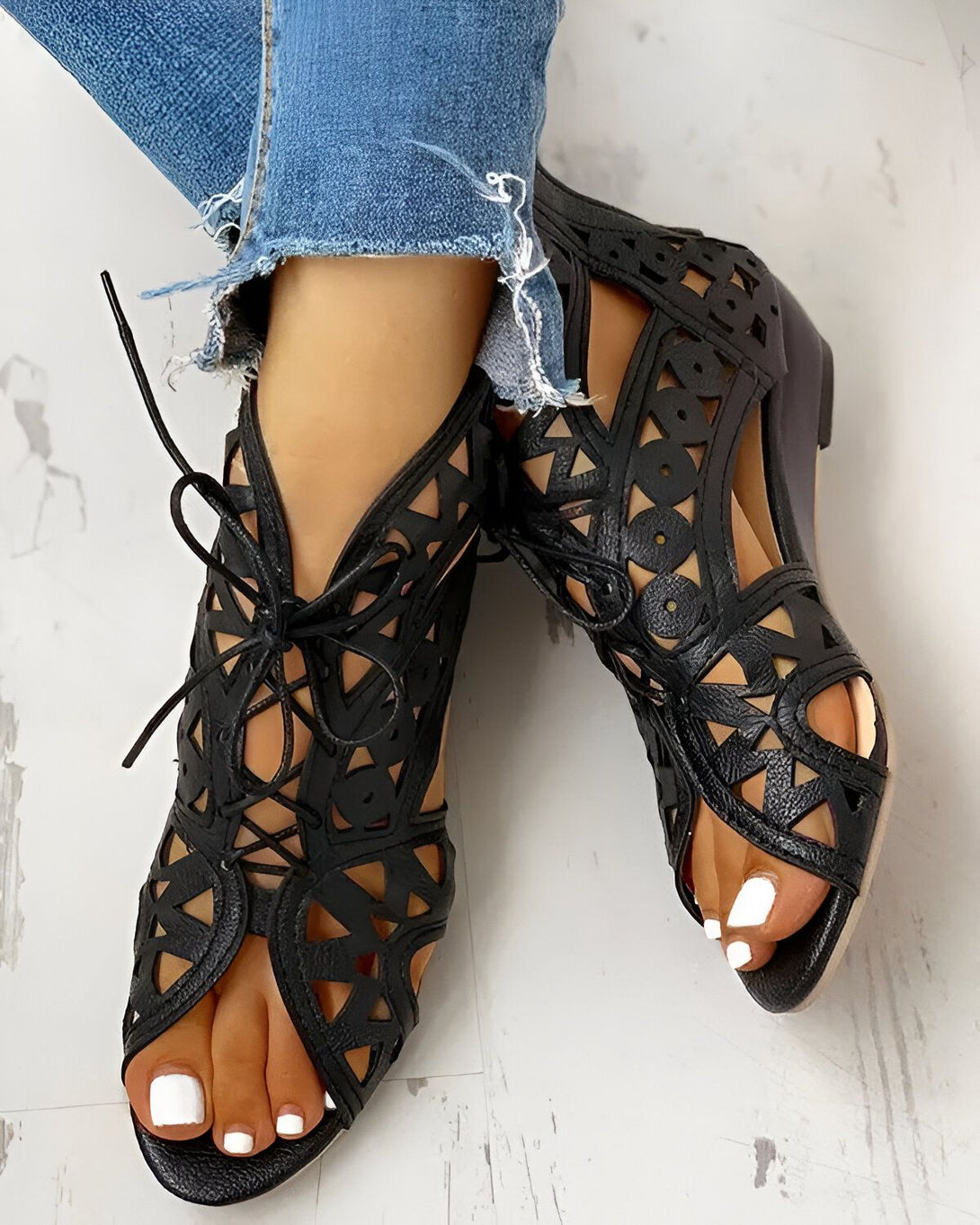 Une paire de sandales noires ajourées avec des lacets.