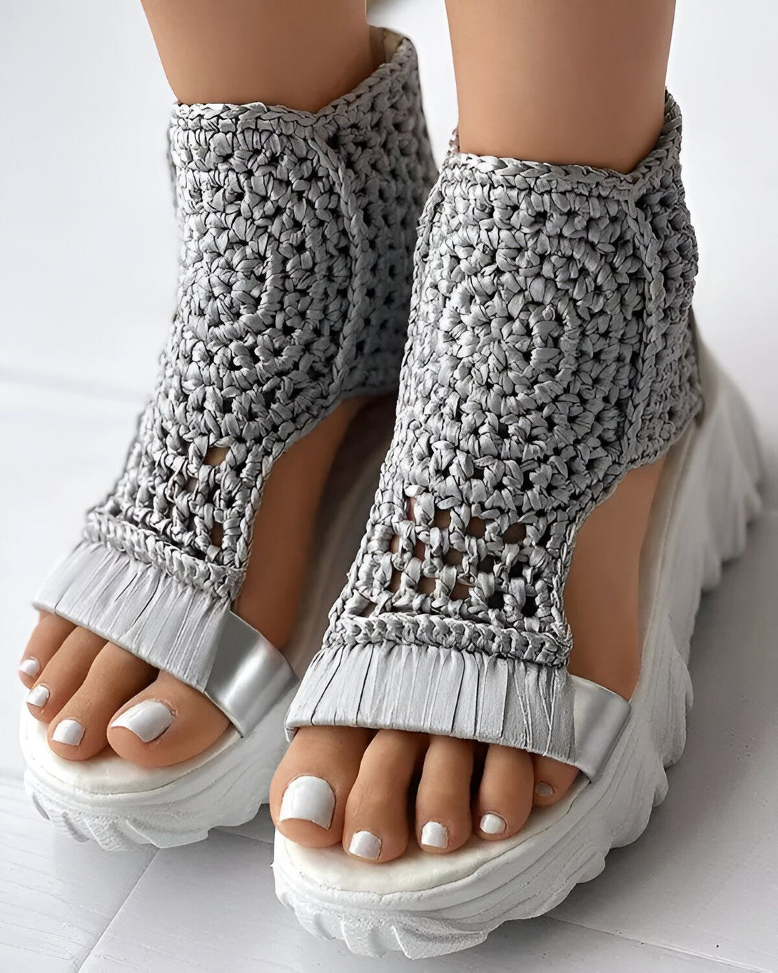 Une paire de sandales compensées grises en crochet avec une bride en cuir.