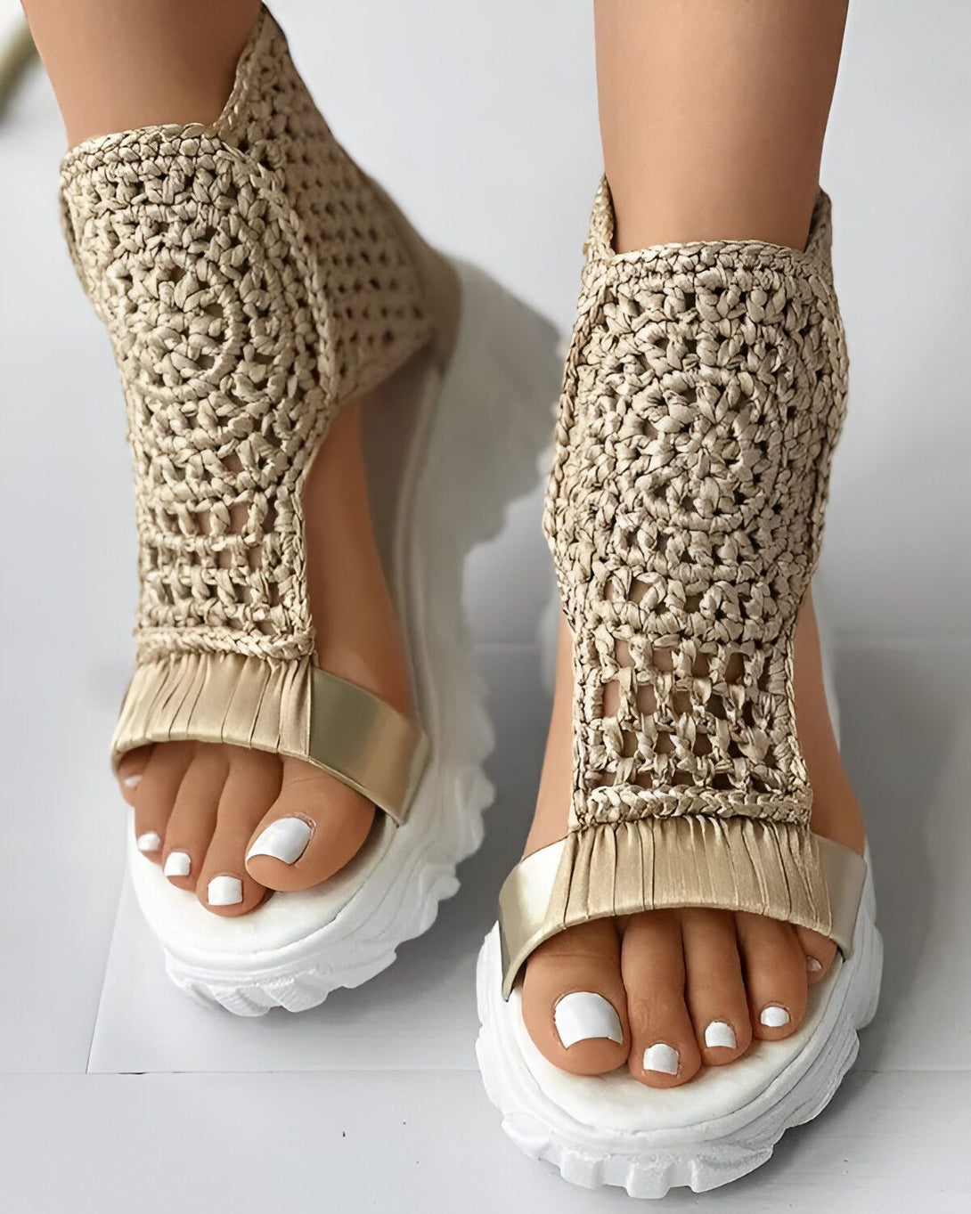Une paire de sandales compensées beiges avec des brides en crochet et une semelle blanche.